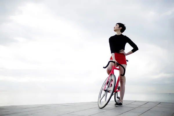 Young woman standing with her modern bicycle — Stockfoto