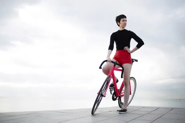Mujer hipster de pie con su bicicleta deportiva — Foto de Stock