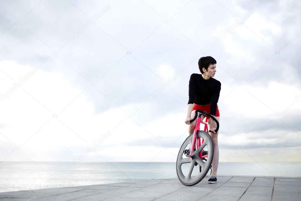 hipster woman sanding with her pink bicycle