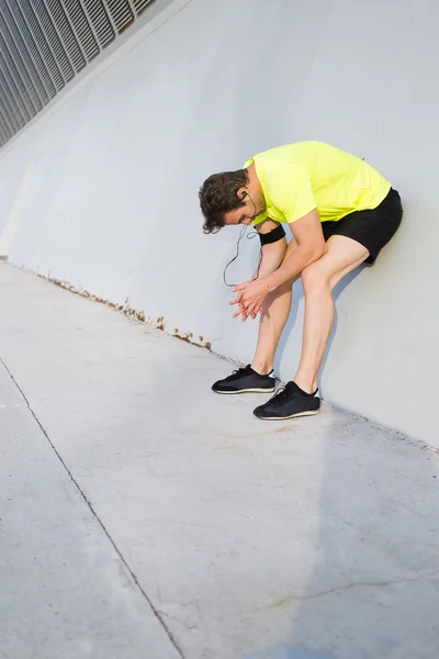 Atleta do sexo masculino inclinado para a parede branca — Fotografia de Stock