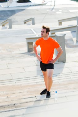 Handsome male runner resting after an active run outdoors in summer