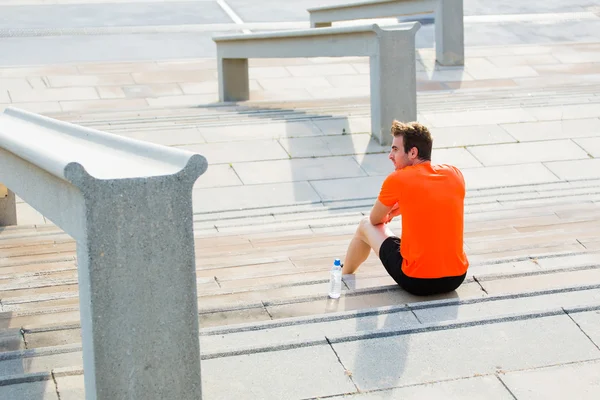 Male athlete sitting on asphalted — Stock Photo, Image