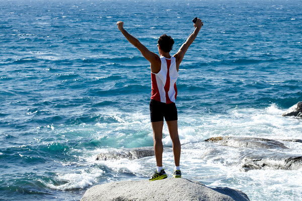 Спортсмен стоит на скале
