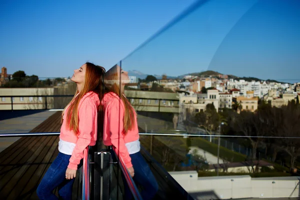 Pretty female standing against glass fence — Stockfoto