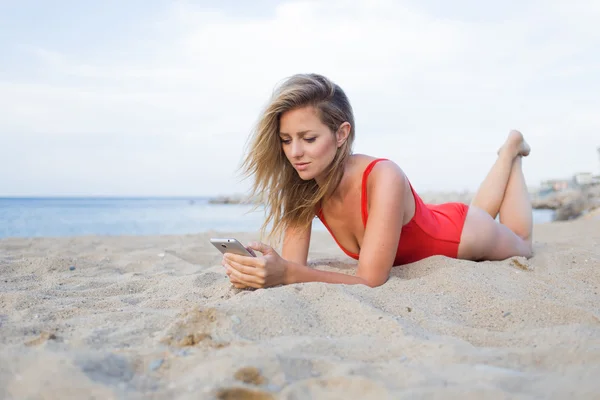 ビーチでスマートフォンを使う女性は — ストック写真