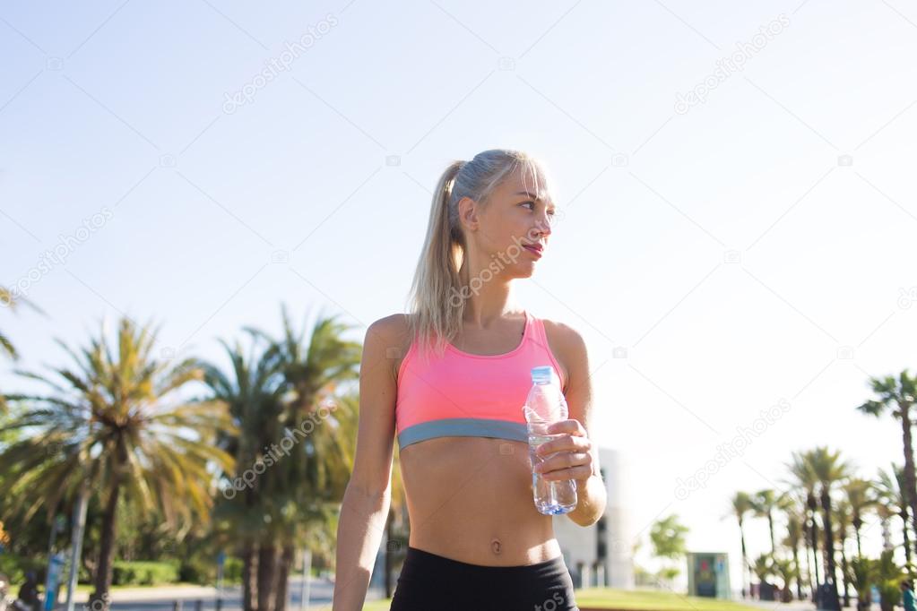 Young sportswoman holding water bottle