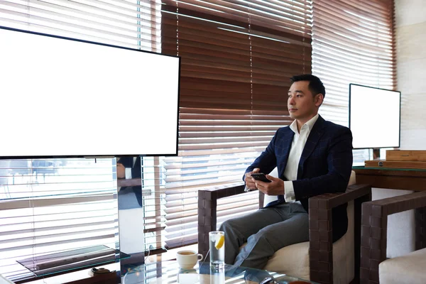 Бизнесмен сидит в офисе рядом с пустым экраном — стоковое фото