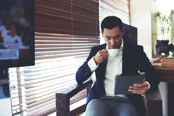 Бизнесмен, сидящий в офисе и пьющий кофе — стоковое фото