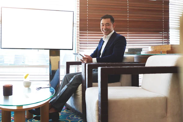Smiling businessman sitting near empty screen — Stok fotoğraf