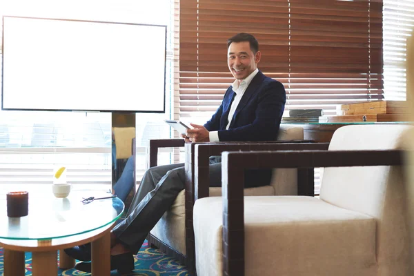 Hombre de negocios sonriente sentado cerca de la pantalla vacía — Foto de Stock