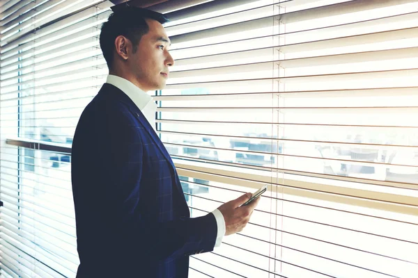 Asiatischer Geschäftsmann steht in der Nähe von Bürofenster — Stockfoto