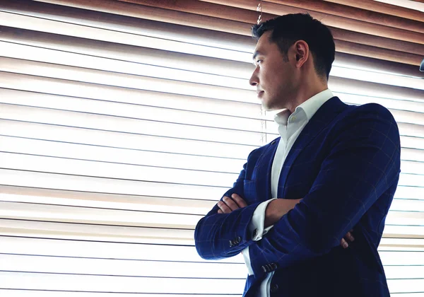 Businessman standing near office window — Stock Photo, Image