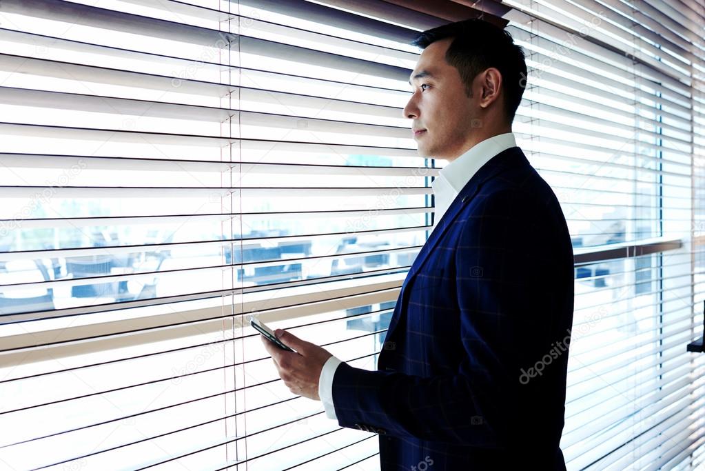 Asian businessman standing near office window