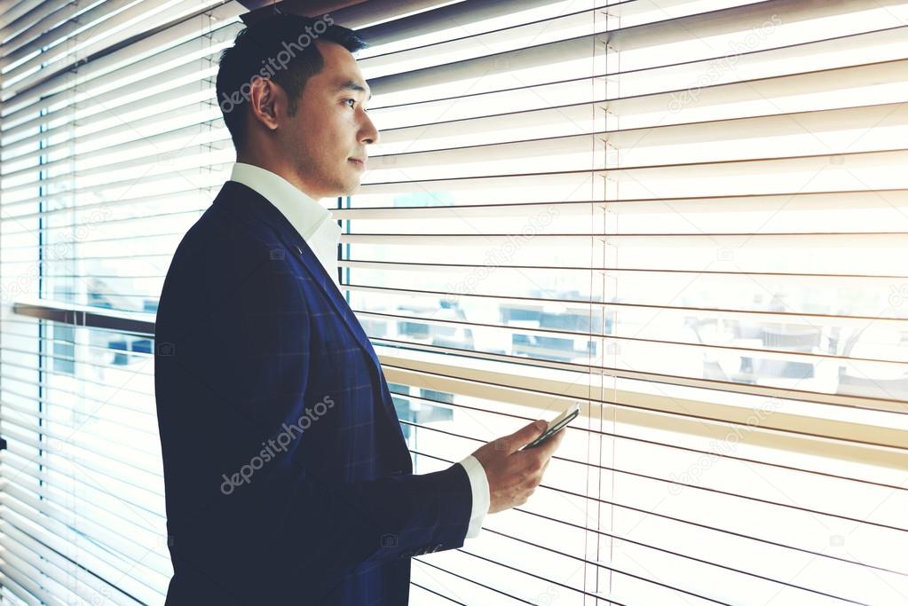 Asian businessman standing near office window