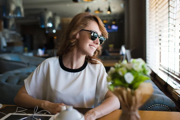 Mujer sentada cerca de ventana en cafetería — Foto de Stock