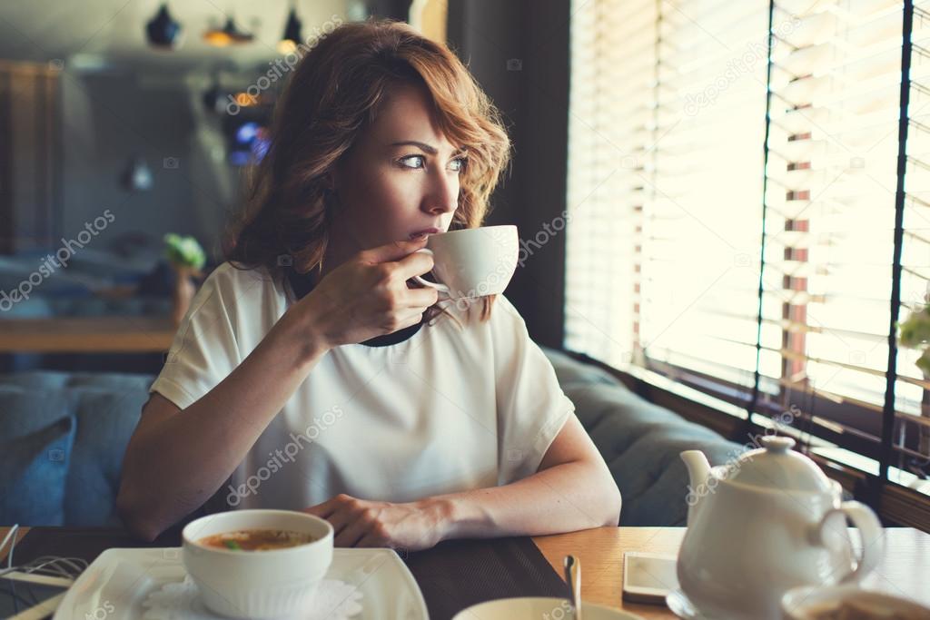 Woman drinking tea in modern cafe