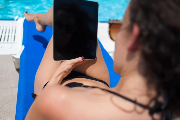 Woman using tablet while sunbathing near pool — Φωτογραφία Αρχείου