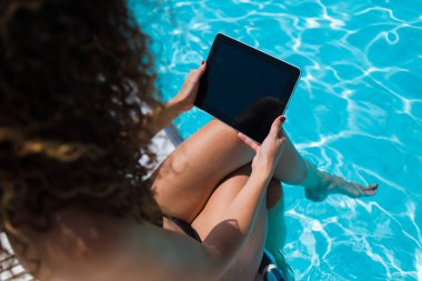 Female in bikini with touch pad near pool