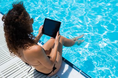 Female in bikini with touch pad near pool