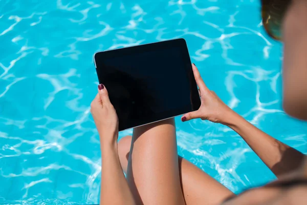 Female in bikini with touch pad near pool