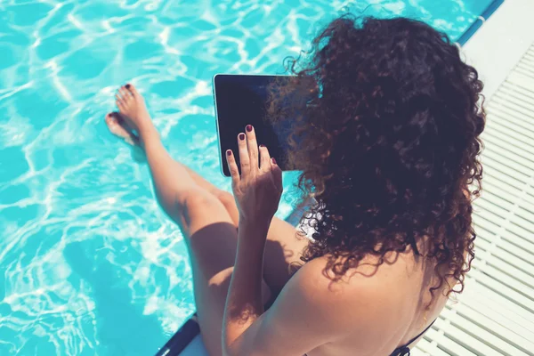 Mujer en bikini con almohadilla táctil cerca de la piscina — Foto de Stock