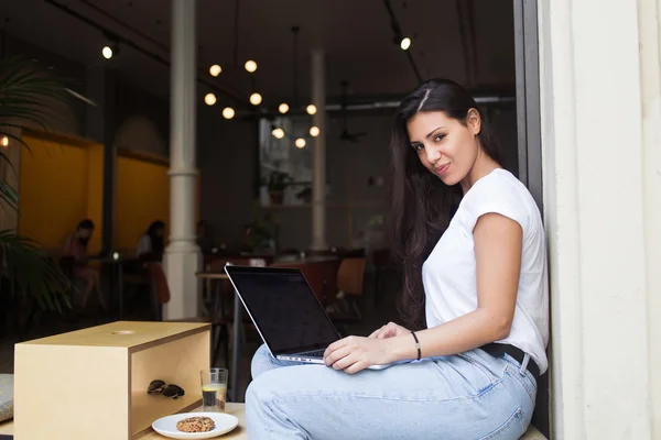 Gadis hipster muda yang mengerjakan buku jaringannya Stok Lukisan  