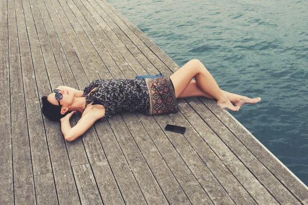 Attractive woman lying on a wooden pier — Stockfoto