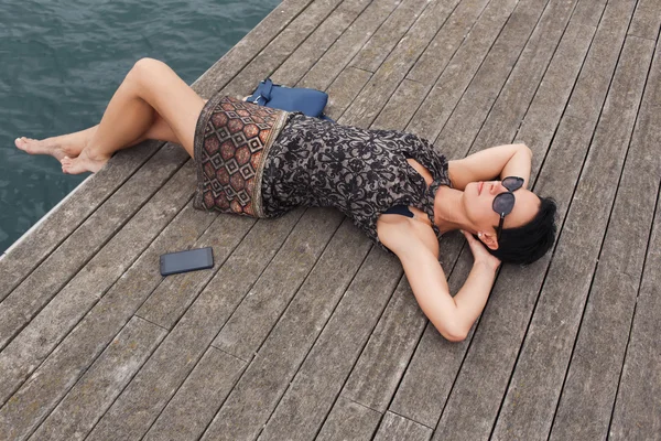 Привлекательная женщина лежит на деревянном пирсе — стоковое фото