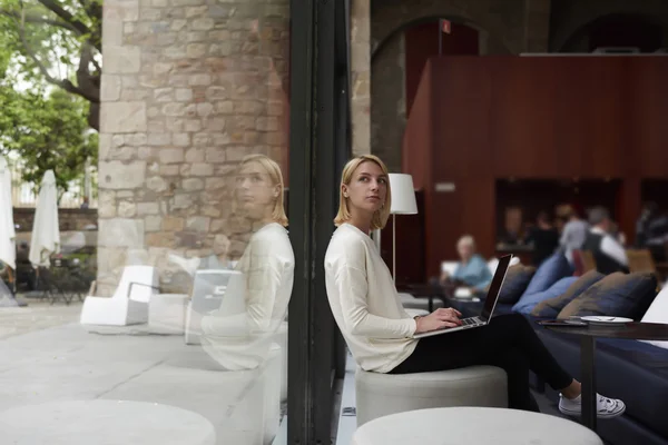 Nainen työskentelee nettikirjan parissa istuessaan kahvilassa — kuvapankkivalokuva