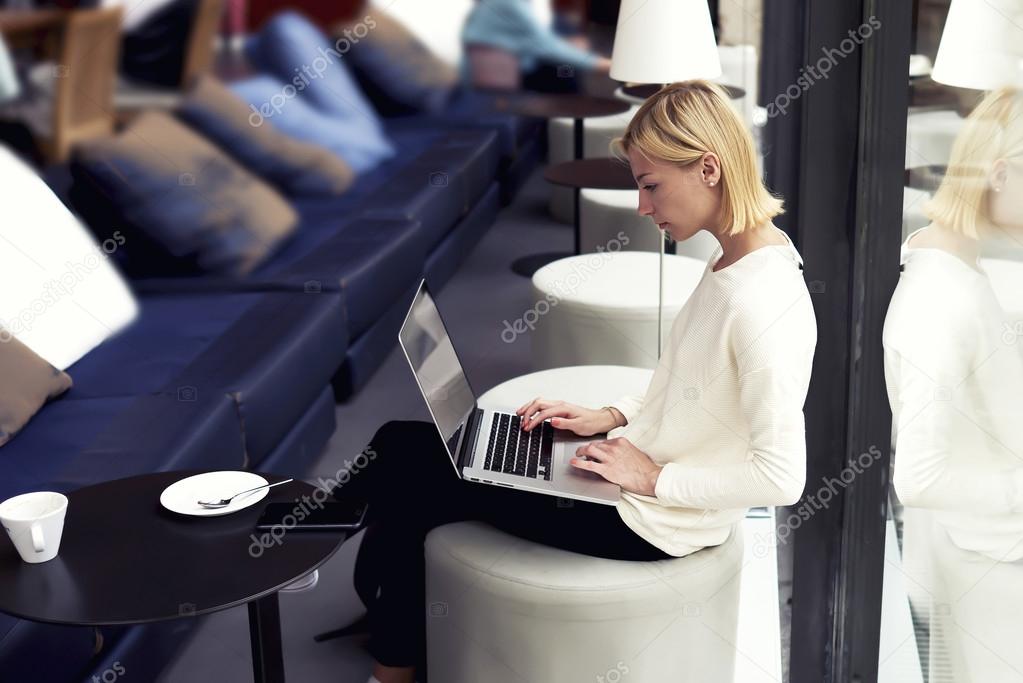 Woman working on net-book while sitting in cafe