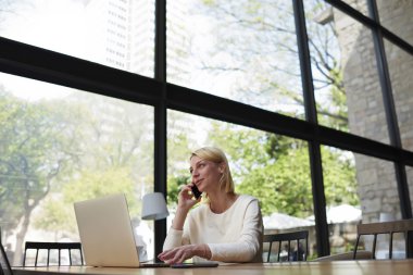 Woman working on net-book and talks on smartphone