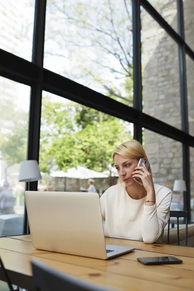 Woman talks on smartphone and looking to net-book — Stock Photo, Image