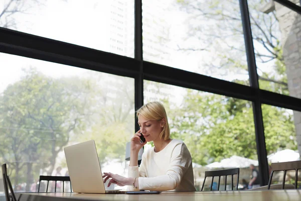 Businesswoman talking on smartphone in modern cafe — Stockfoto