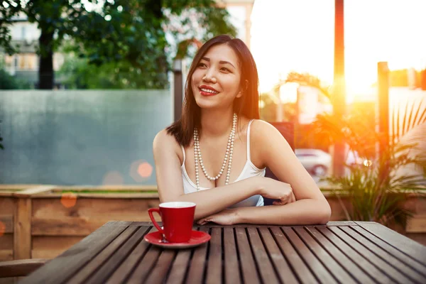 Smiling asian woman sitting in cafe — Stock Photo, Image