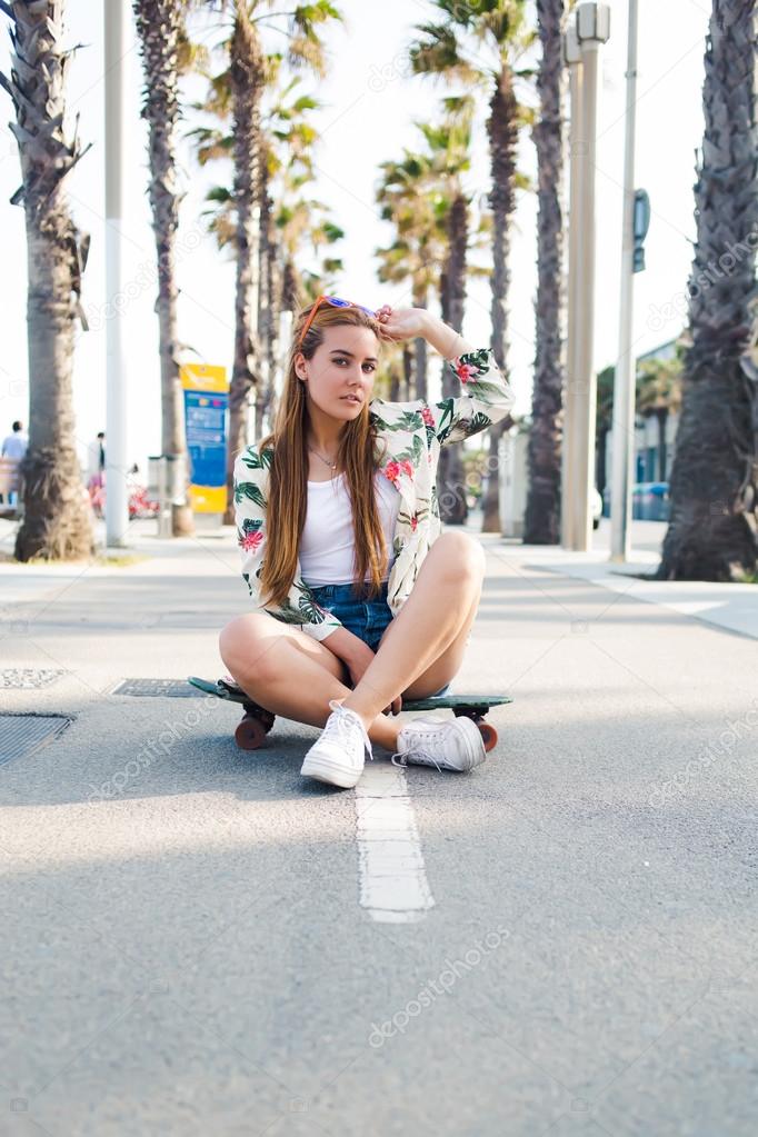 Trendy woman sitting on longboard