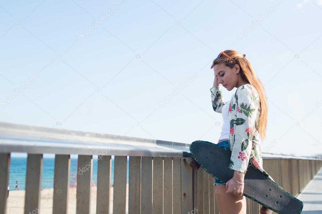 Woman with longboard while standing on bridge