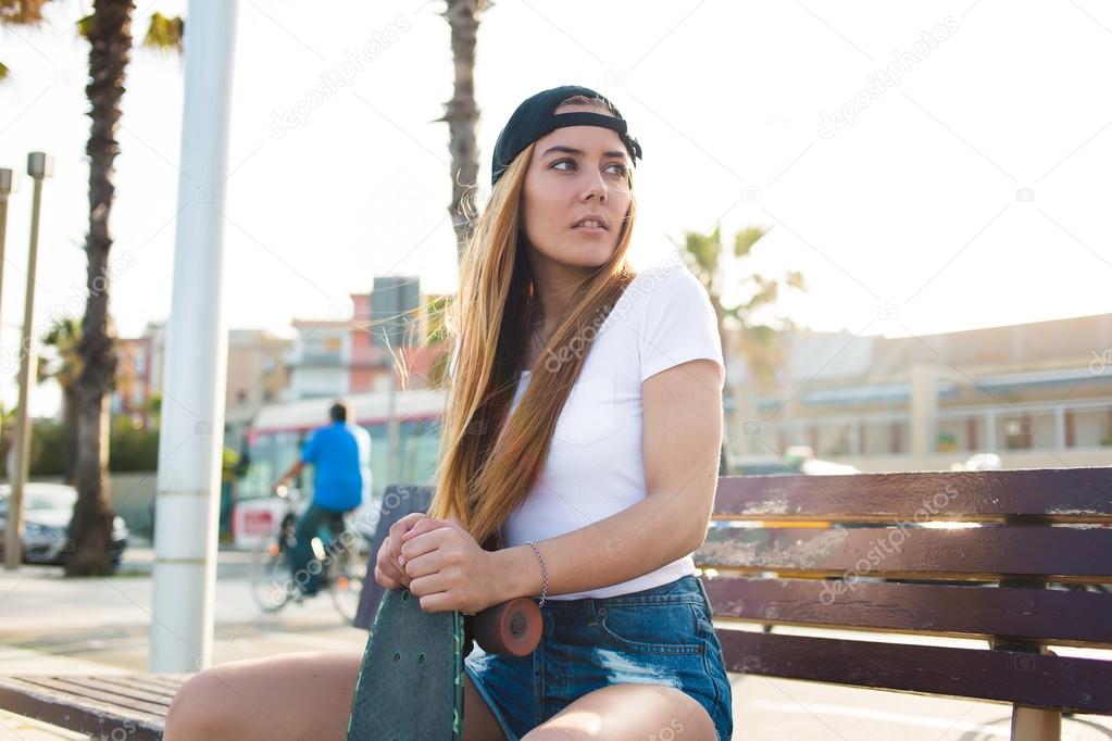 Woman skateboarder sitting  with penny board