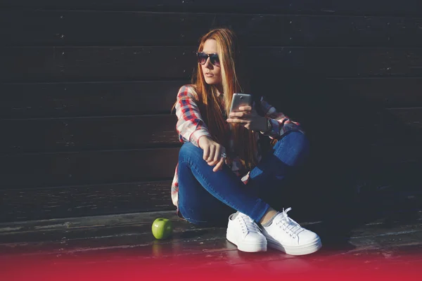 Хипстерская девушка использует свой смартфон на открытом воздухе — стоковое фото
