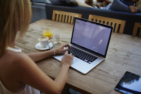 Vue de dos d'une jeune femme assise devant un ordinateur portable portable ouvert avec écran d'espace de copie vierge, pigiste féminine utilisant le net-book pour le travail à distance pendant le petit déjeuner du matin dans un café bar — Photo