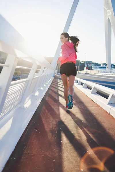 Athletic woman running on the bridge — Stok fotoğraf