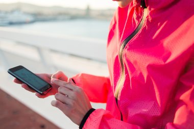Sportswoman hands using mobile phone
