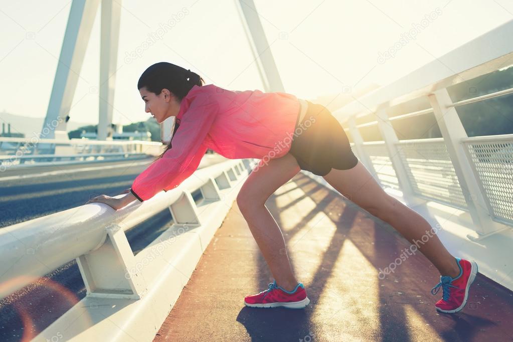 Sportswoman stretching muscles before start