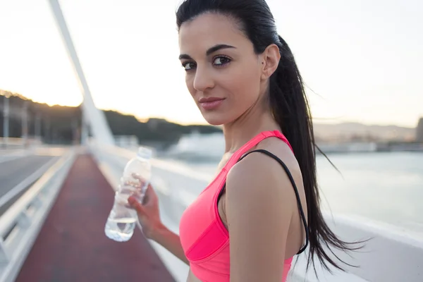 Athletic woman holding bottle of water — Stock fotografie