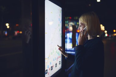 Woman touching digital display on bus stop