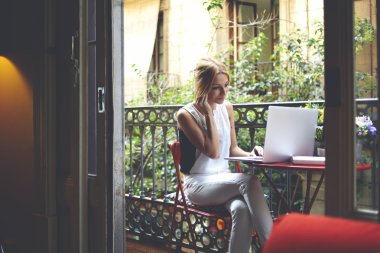 Woman working on laptop computer at balcony