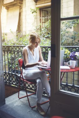 Woman working on laptop computer at balcony