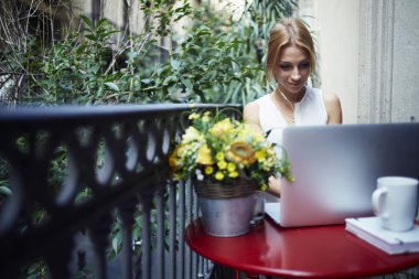 Woman working on laptop computer at balcony