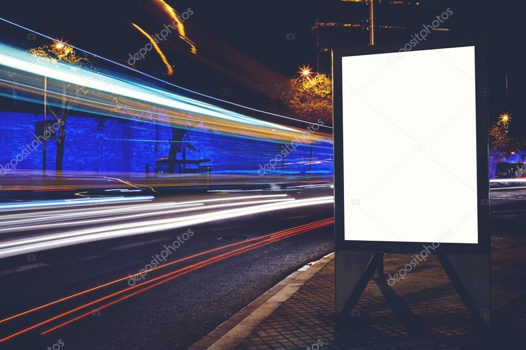 Illuminated empty electronic billboard with copy space for your text message or content, advertising mock up with movement of car on the background, blank public information board on roadside at night