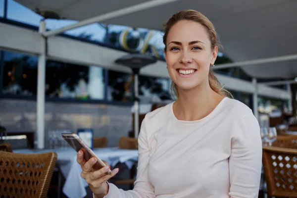 Mujer sonriente sosteniendo el teléfono móvil — Foto de Stock