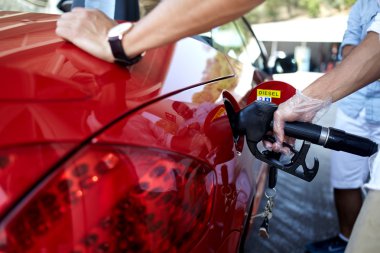 man's hand pumping gasoline fuel